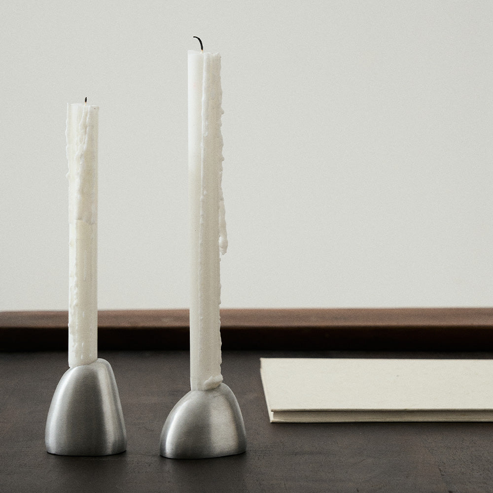 matgepolijste aluminium kandelaar voor lange kaarsen van Uncharted Out of Lines met kaarsen er in op een zwarte tafel