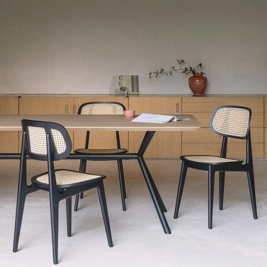 Titus-stoel met gevlochten leuning en zitting aan een tafel