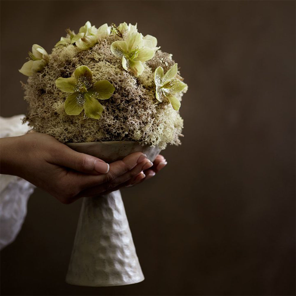 een handgemaakte standaard voorzien van een matte glazuur met bloemen er in