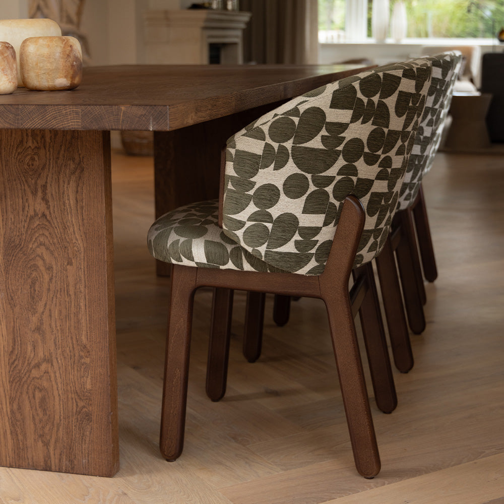 Mika stoel met zachte, geweven bekleding met print en houten poten aan een tafel