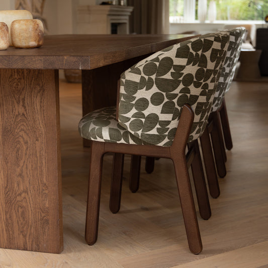 Mika stoel met zachte, geweven bekleding met print en houten poten aan een tafel