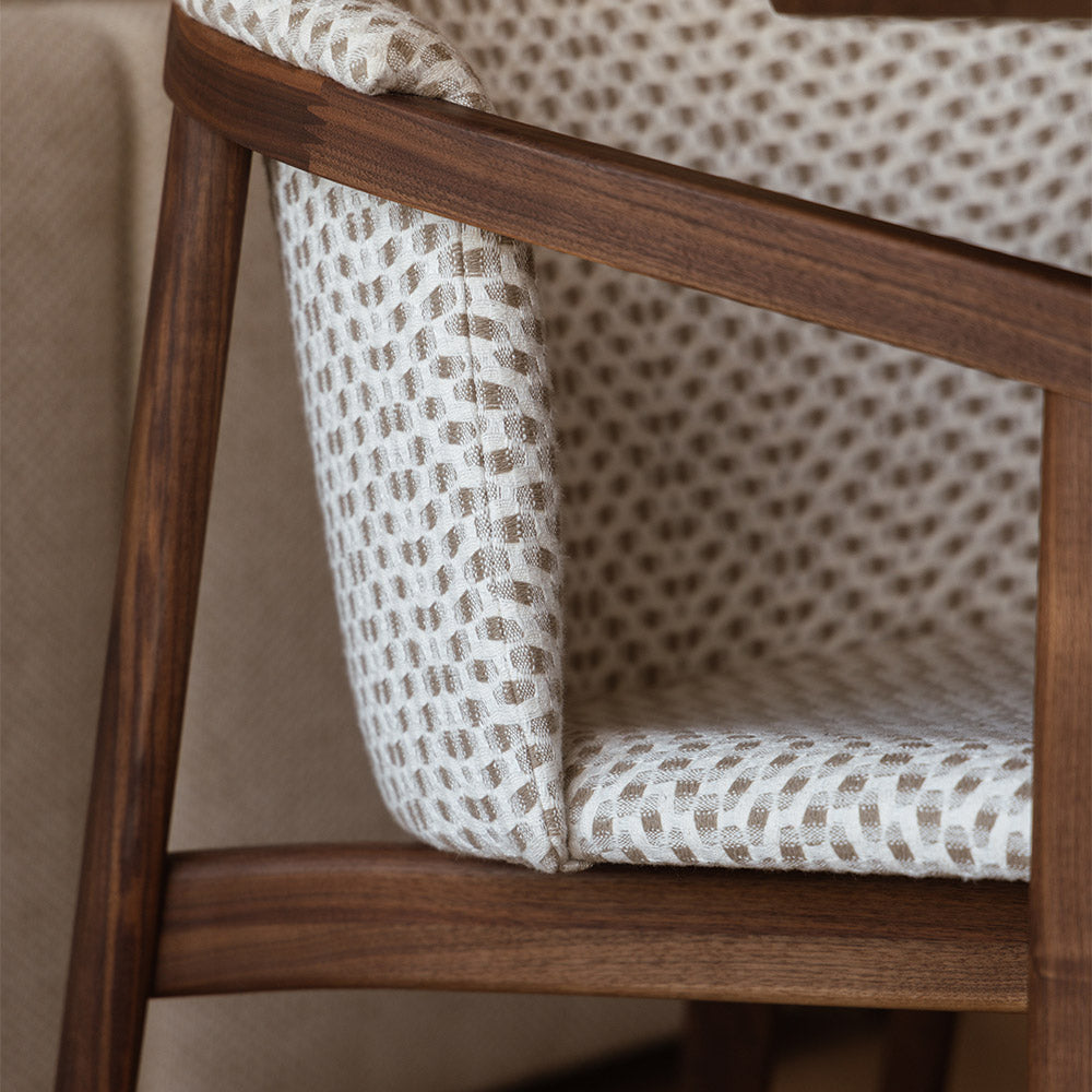 close-up van zijkant van eetstoel van notenhout en stof met armleuning