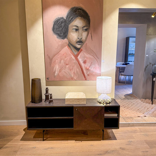 A-symmetrisch dressoir van Mindi hout met decoratie er op met een schilderij van grace spiegel tentoongesteld in de showroom