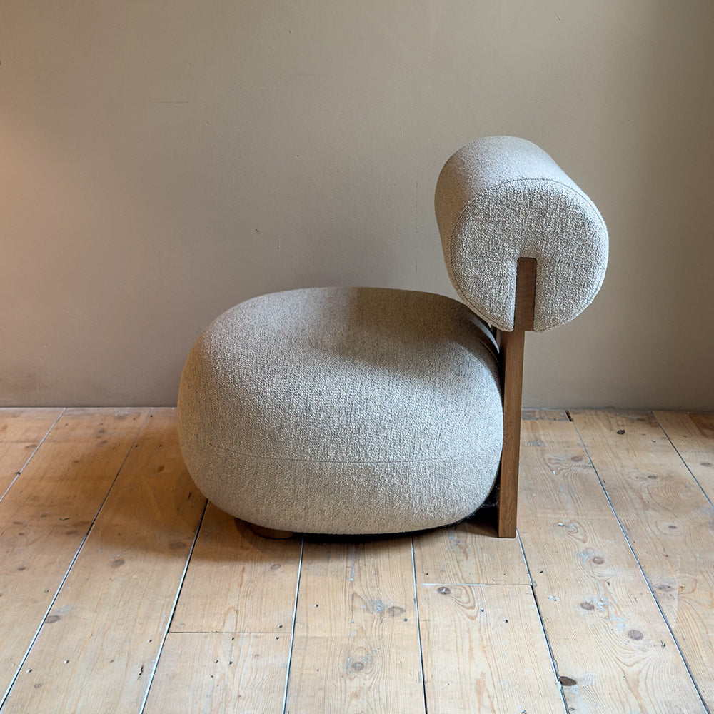 zijkant van hippo lounge stoel met houten omlijning en met zachte rugleuning en bolle zitting voor een muur