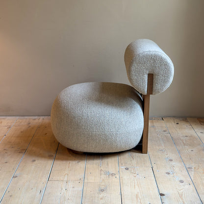zijkant van hippo lounge stoel met houten omlijning en met zachte rugleuning en bolle zitting voor een muur